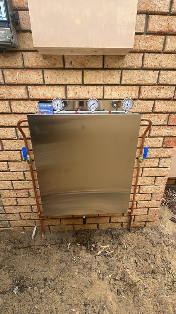 Licensed gas-fitter connecting a stainless gas cooktop in a kitchen benchtop